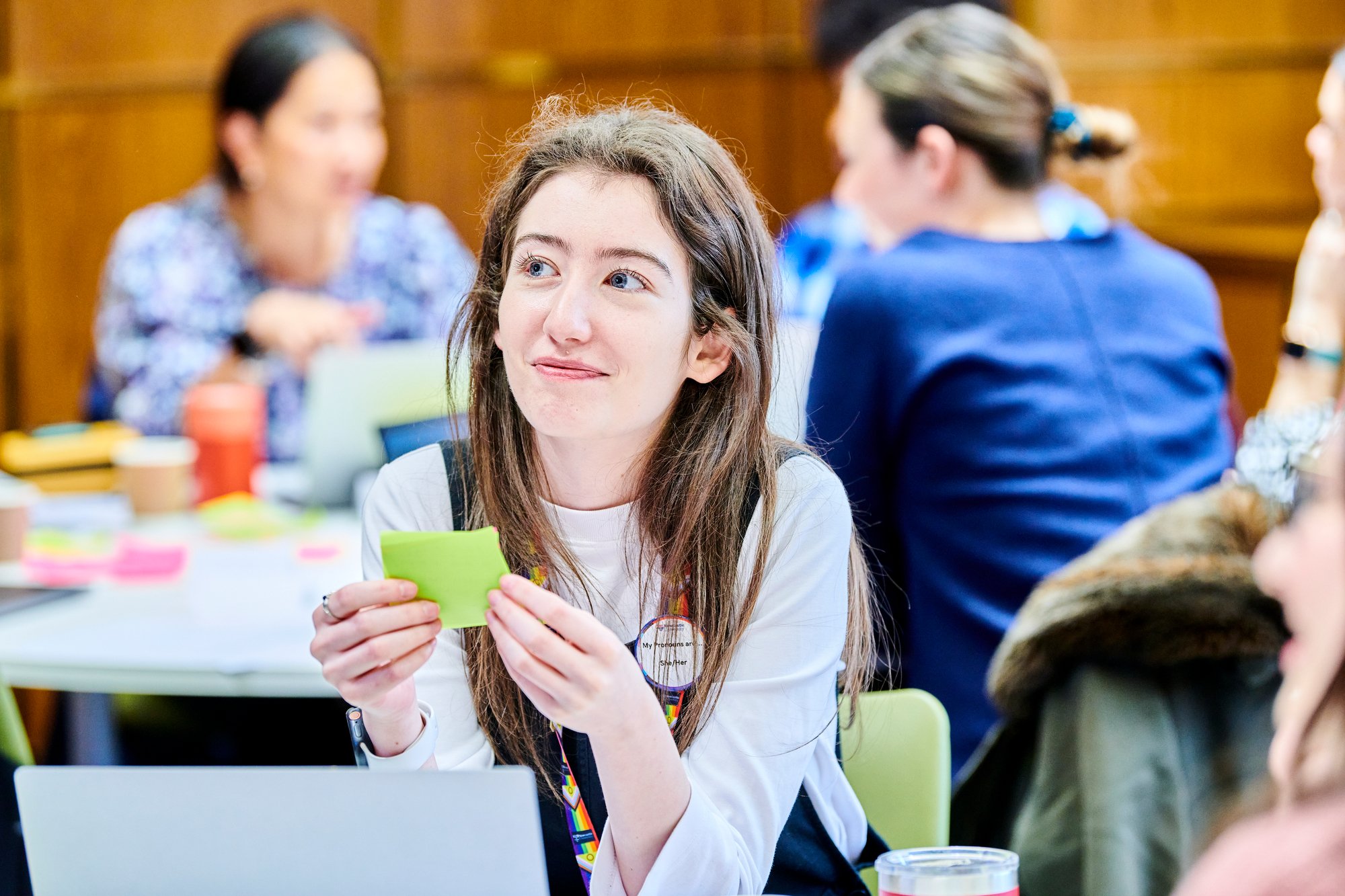 A woman smiling and holding notes while attending the Equality, Diversity, and Inclusion workshop.